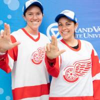 Two alumnae pose together, wearing Red Wings jerseys at the Detroit Red Wings GVSU Night